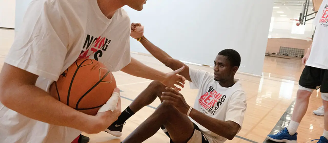 Basketball players assist each other and  help each other up in a basketball game and remember that empathy is crucial to building great teams.