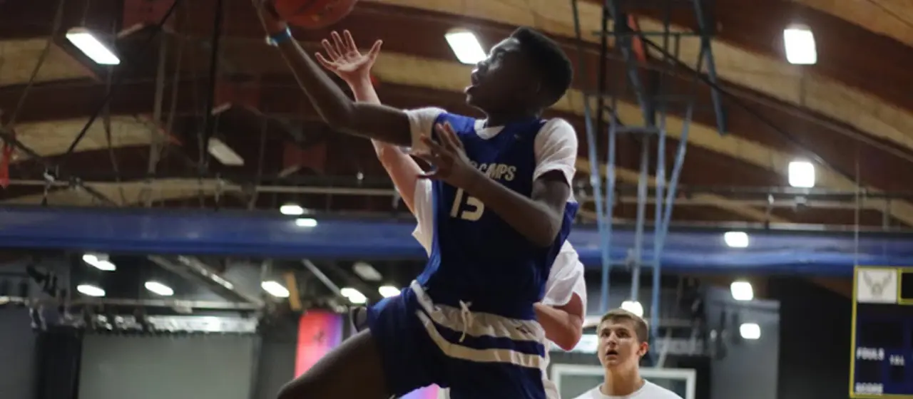 Athlete uses an underhand lay up in basketball tournament game between NBC Travel Teams and Auburn All-Stars.