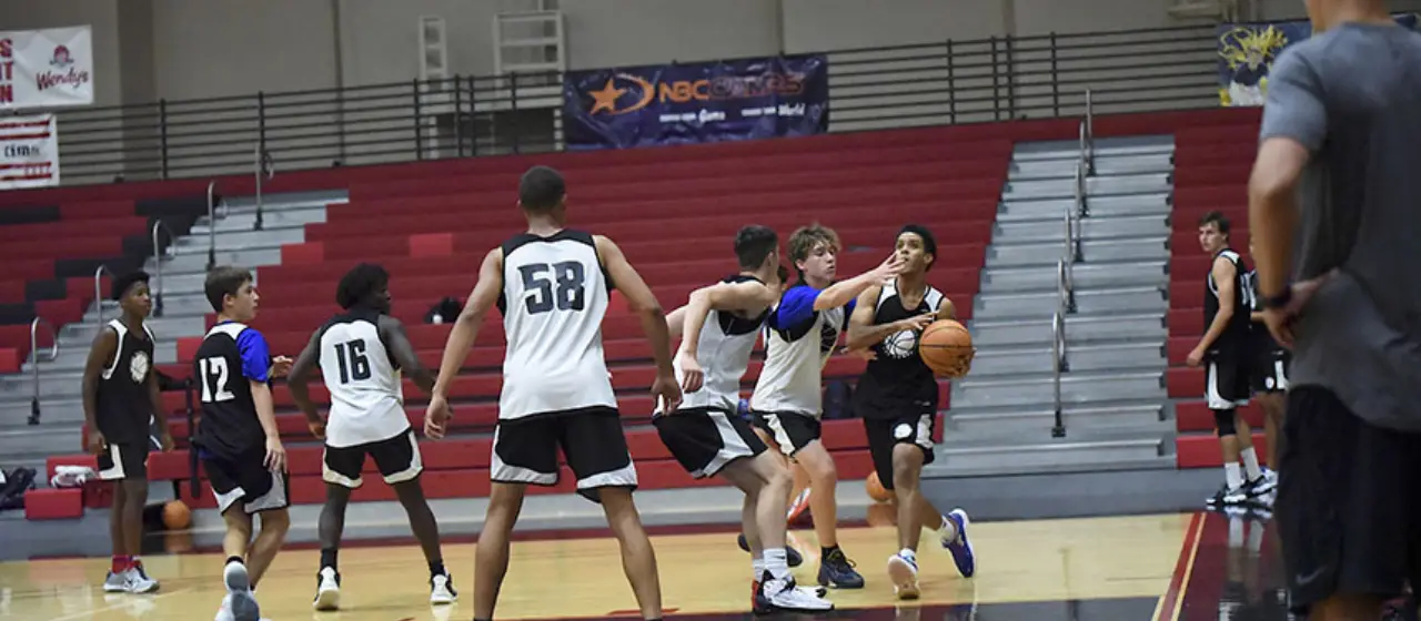 Coach watches from the baseline during basketball game at NBC Camps.