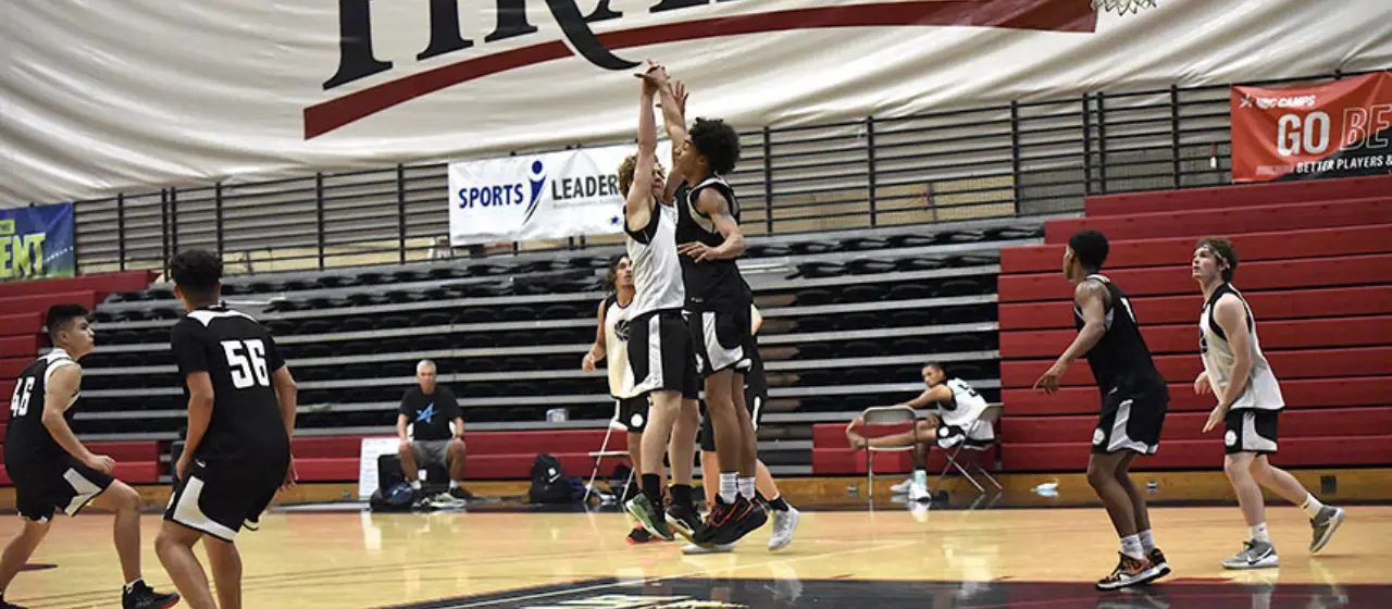 Basketball camper avoids blocked shot during camp tournament play.
