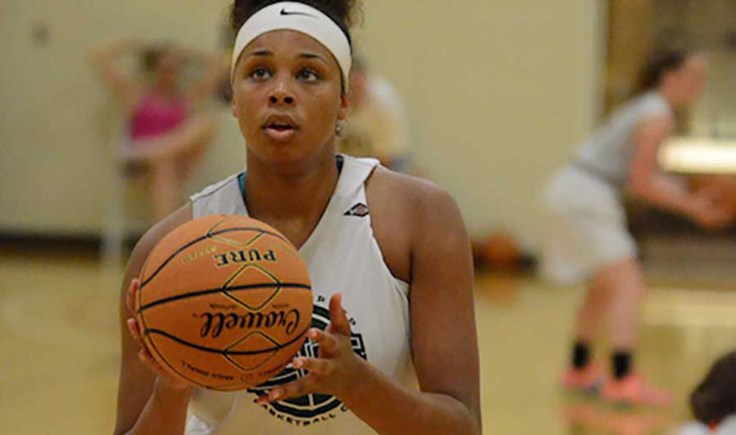 Female athlete focuses on free throw shooting routine during basketball camp training session.