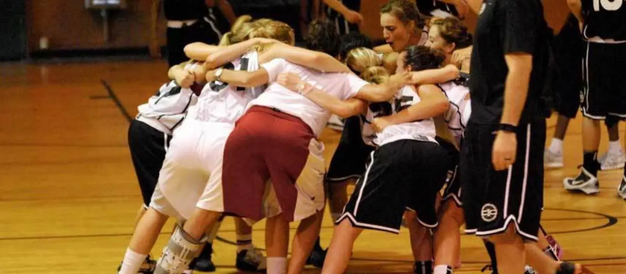 Girls have fun in basketball camp huddle after tournament win.