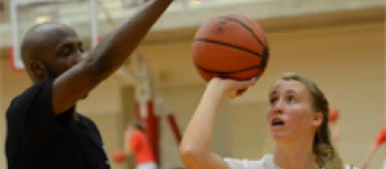 Coach adjusts camper's shooting form
