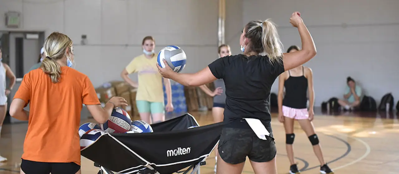 Coach demonstrates serving expectations to volleyball campers