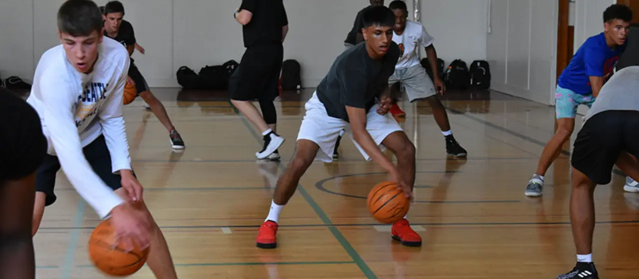 Basketball players work on ball handling skills at summer basketball camp.